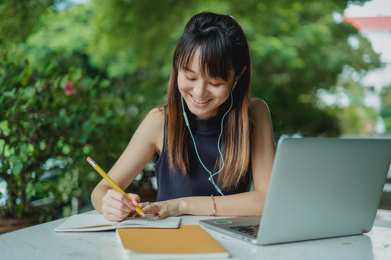 student taking at laptop studying and smiling for one-to-one language lessons